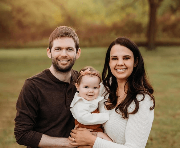 Doctor Schlemmer smiling with her husband and daughter outdoors